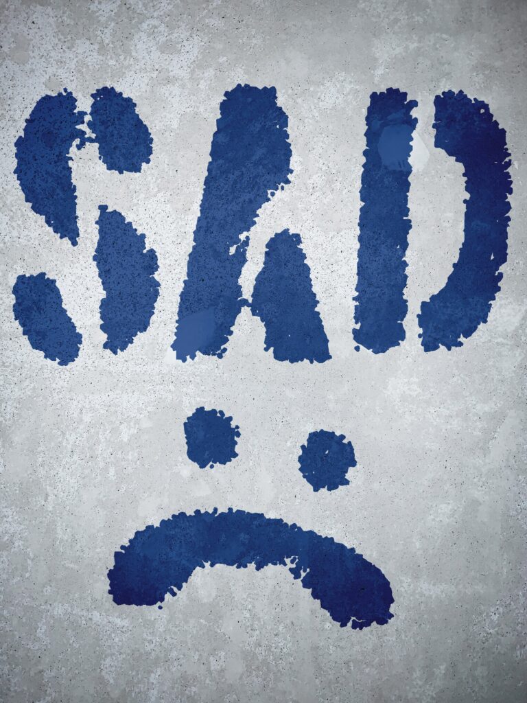 Written sad letters with sad face. Painted in blue color. Show depressed.